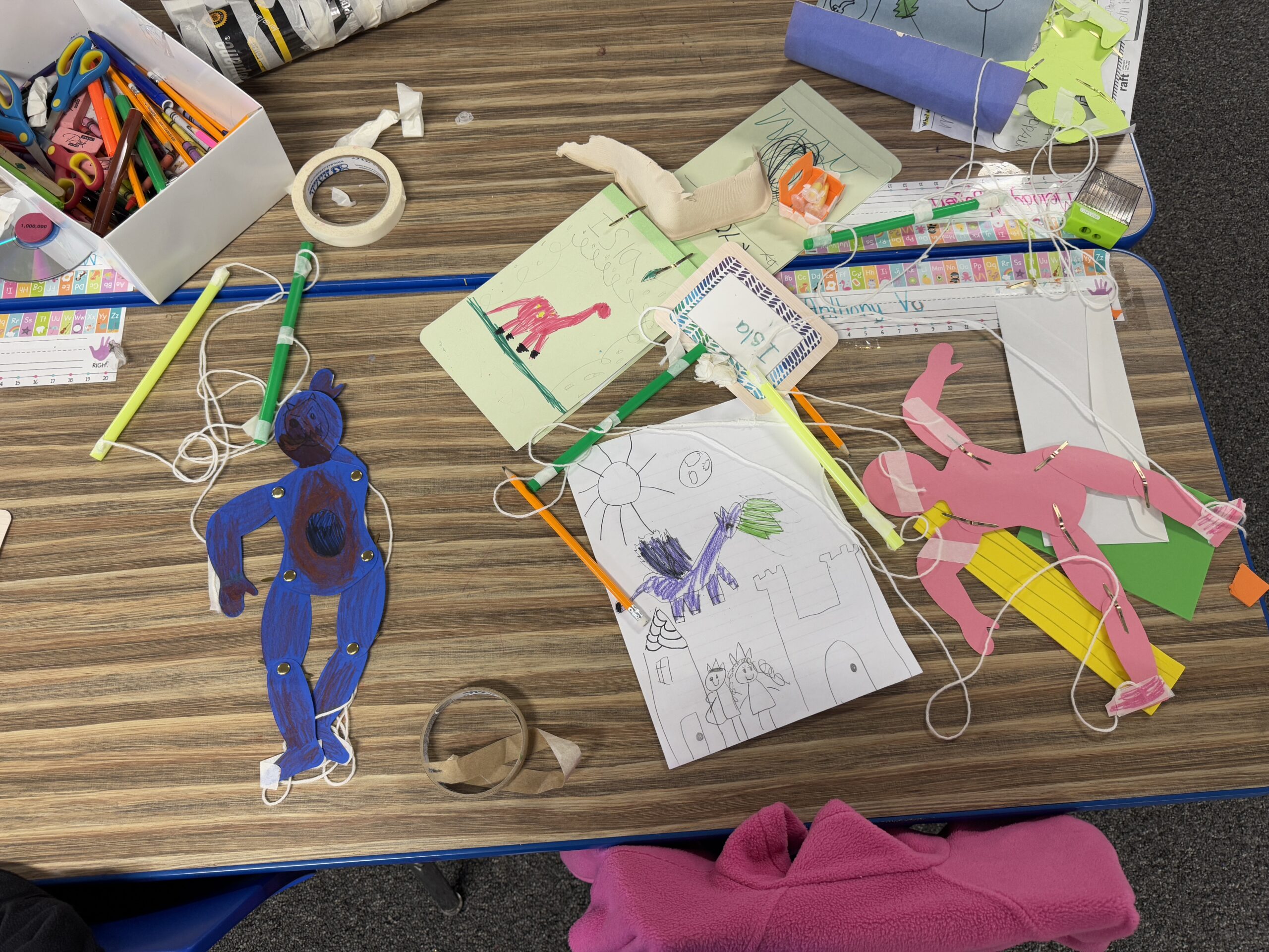 Student-made marionette puppets displayed with crafting materials in a creative workspace.